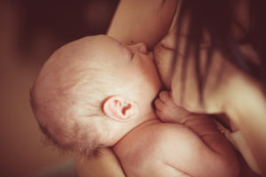 Pieni vauva imee rintaa ihokontaktissa.
