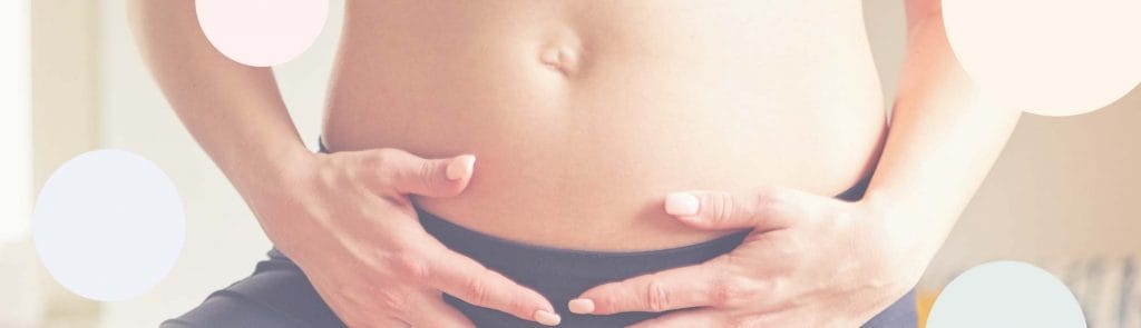 Nainen pitää käsiään alavatsalla.