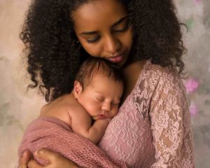 Äiti pitää sylissään rintakehäänsä vasten pientä nukkuvaa vauvaa. Äidillä on silmät kiinni ja molemmilla rauhallinen ilme.