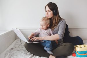 Vanhempi tekee töitä läppärillä, taapero auttaa sylissä