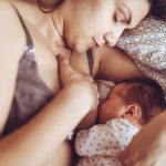 Vanhempi imettää perhepedissä vauvaansa.