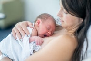 Vastasyntynyt vauva hamuilee ihokontaktissa viltin alla