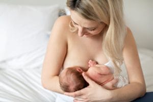 Vanhempi imettää pientä vastasyntynyttä istuen